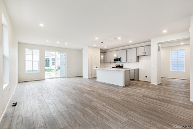 kitchen with gray cabinets, decorative light fixtures, a center island, and light hardwood / wood-style floors