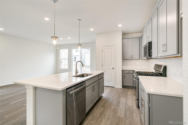 kitchen with a kitchen island with sink, sink, gray cabinets, appliances with stainless steel finishes, and light hardwood / wood-style floors