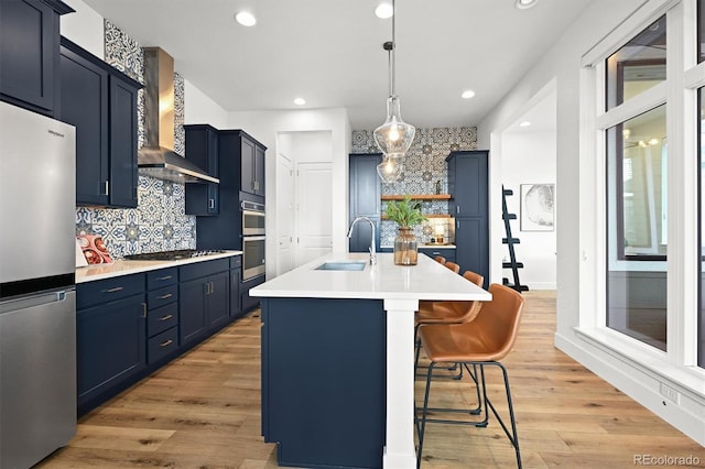 21440 E 61st Dr, Aurora, CO 80019 - kitchen featuring stainless steel appliances, a sink, wall chimney range hood, blue cabinets, and recessed lighting