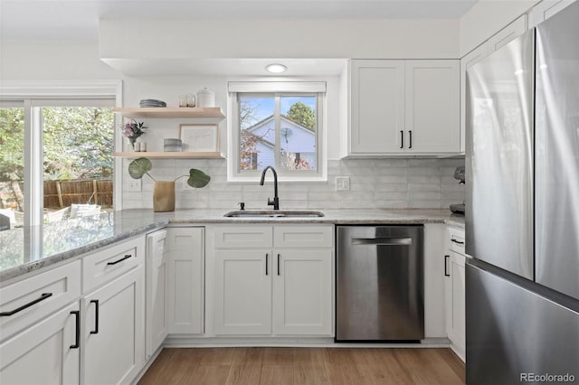 10801 W 29th Ave, Lakewood, CO 80215 - kitchen with a sink, light wood finished floors, stainless steel appliances, white cabinetry, and backsplash
