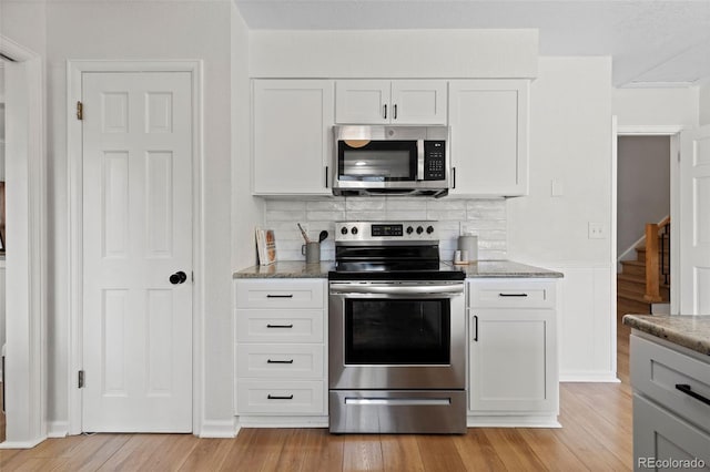 10801 W 29th Ave, Lakewood, CO 80215 - kitchen with white cabinetry, appliances with stainless steel finishes, decorative backsplash, and light wood-style flooring
