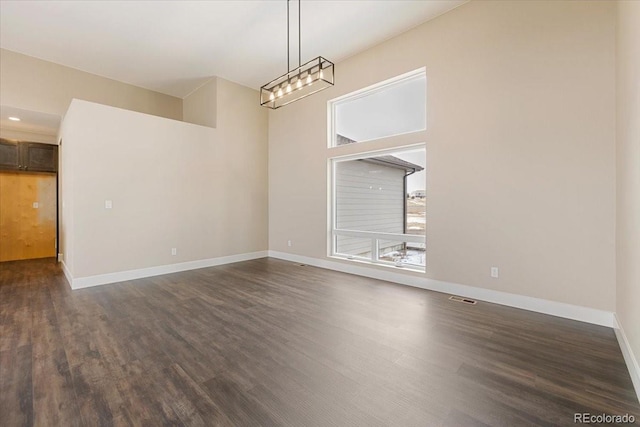 unfurnished room featuring a high ceiling and dark wood-type flooring