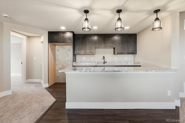 kitchen with pendant lighting, dark hardwood / wood-style flooring, light stone countertops, and sink