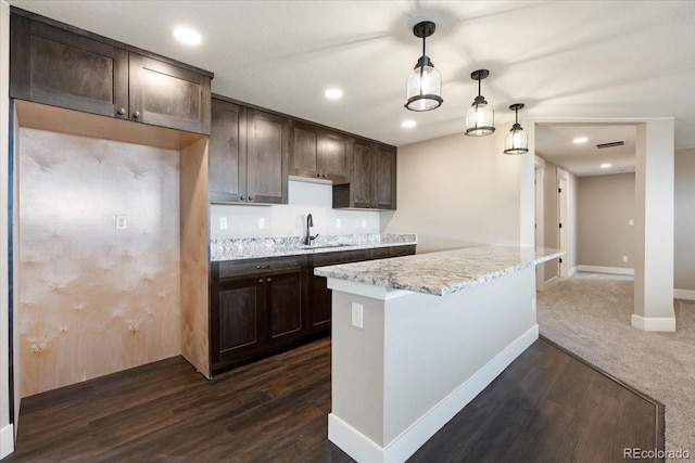 kitchen featuring light stone countertops, sink, pendant lighting, and dark hardwood / wood-style flooring