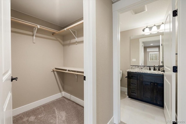 walk in closet featuring sink and light carpet