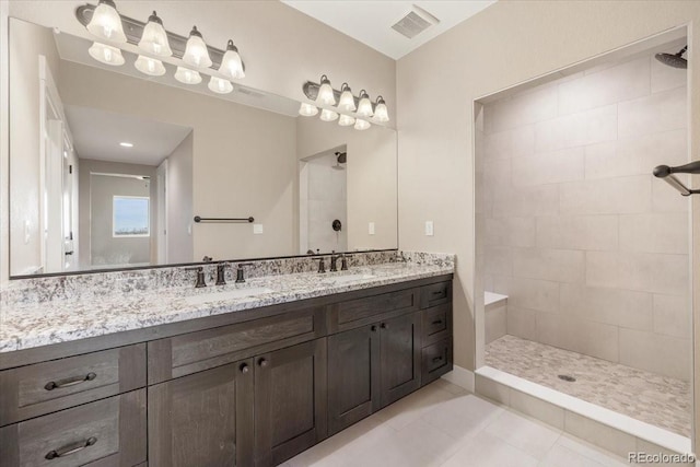 bathroom with tile patterned flooring, vanity, and tiled shower