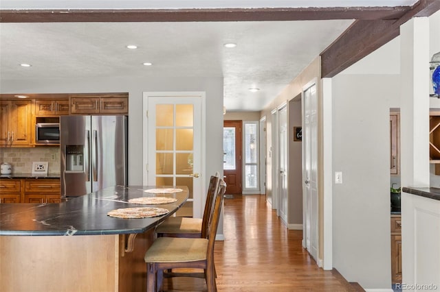4810 W 102nd Pl, Westminster, CO 80031 - kitchen with stainless steel appliances, dark countertops, a breakfast bar area, brown cabinetry, and recessed lighting