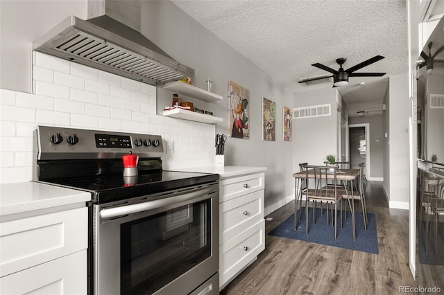 2271 Coronado Pkwy N Unit D, Denver, CO 80229 - kitchen with stainless steel range with electric stovetop, wall chimney range hood, wood finished floors, white cabinets, and tasteful backsplash