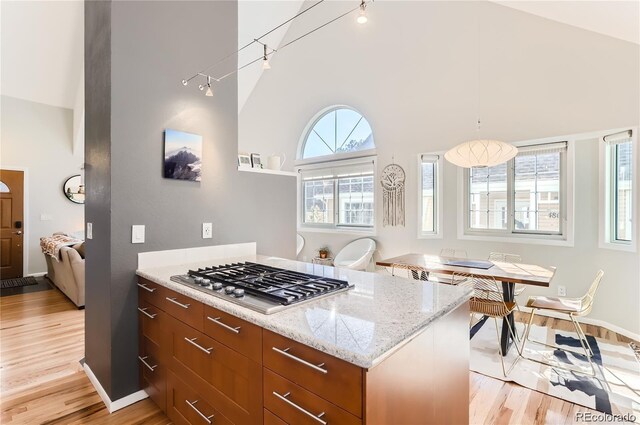 4861 Curie Ct, Boulder, CO 80301 - kitchen featuring stainless steel gas cooktop, high vaulted ceiling, light wood-type flooring, light stone counters, and baseboards