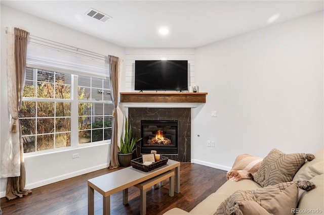 living room featuring a high end fireplace and dark hardwood / wood-style flooring