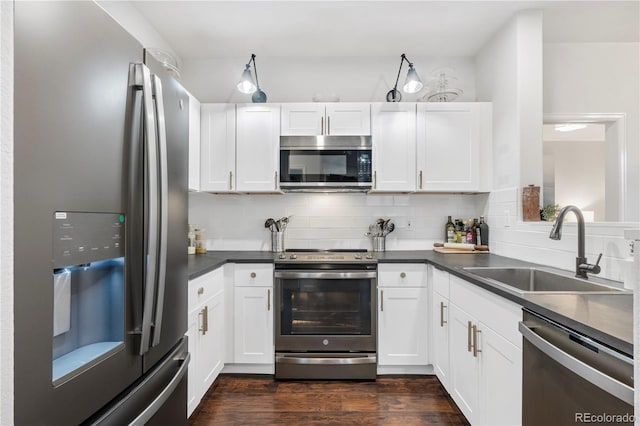 kitchen featuring tasteful backsplash, sink, white cabinetry, appliances with stainless steel finishes, and dark wood-type flooring