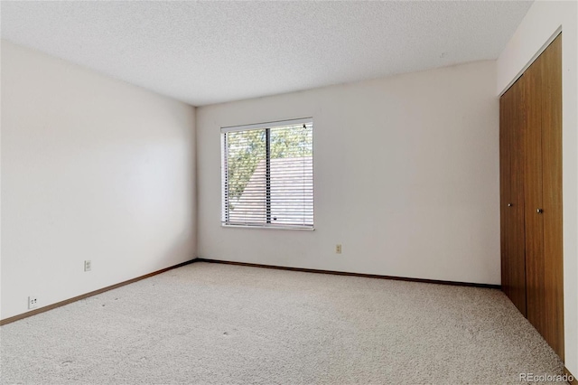 spare room featuring a textured ceiling and light colored carpet