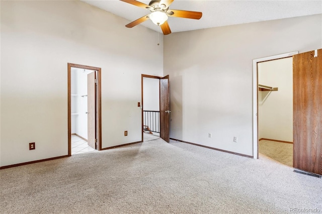 carpeted empty room with high vaulted ceiling and ceiling fan