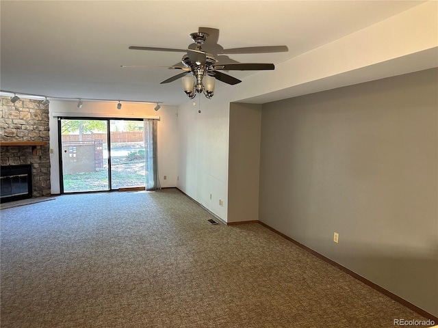 unfurnished living room featuring rail lighting, carpet flooring, a fireplace, and ceiling fan