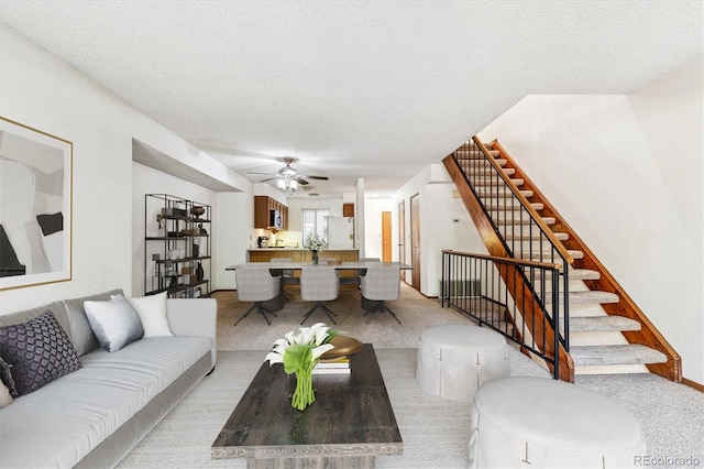 living room featuring a textured ceiling, light colored carpet, and ceiling fan