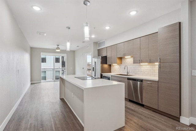 kitchen with visible vents, backsplash, appliances with stainless steel finishes, a sink, and wood finished floors