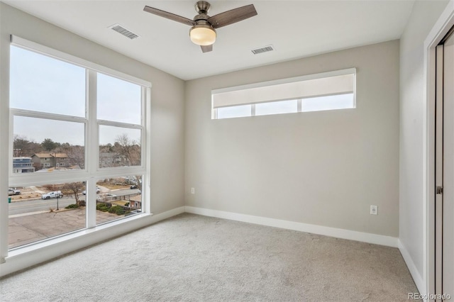 carpeted spare room featuring visible vents, baseboards, and a ceiling fan