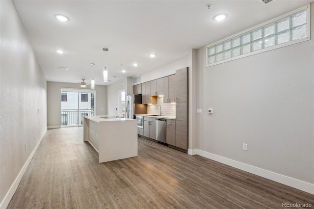 kitchen featuring stainless steel appliances, a kitchen island, decorative backsplash, light wood finished floors, and modern cabinets