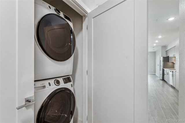 clothes washing area featuring recessed lighting, stacked washer and clothes dryer, and laundry area