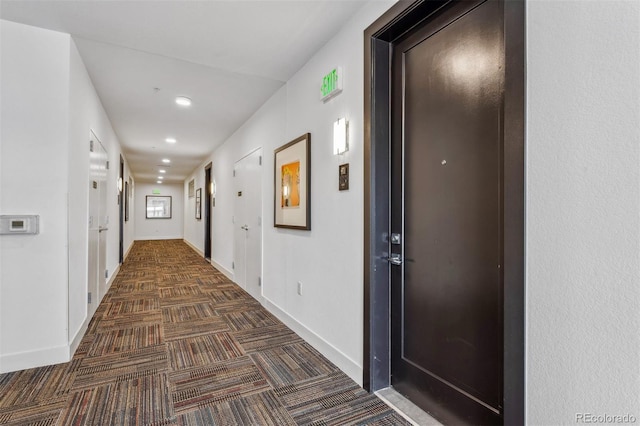 hallway with dark colored carpet, baseboards, and recessed lighting