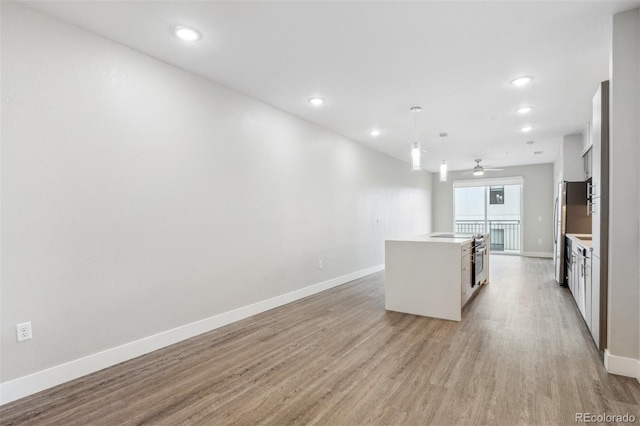 3500 S Corona St Unit 409, Englewood, CO 80113 - kitchen with light wood finished floors, freestanding refrigerator, baseboards, ceiling fan, and a kitchen island