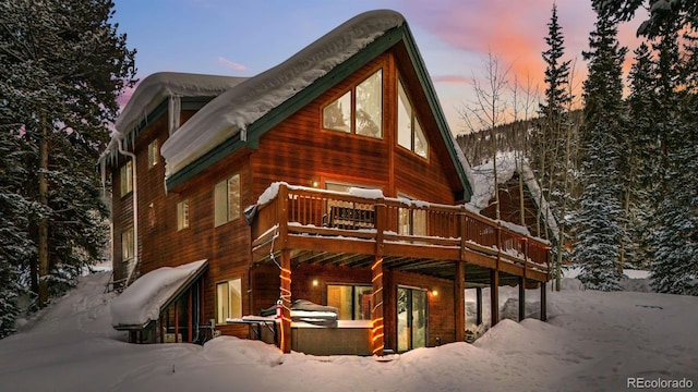 snow covered house featuring a wooden deck