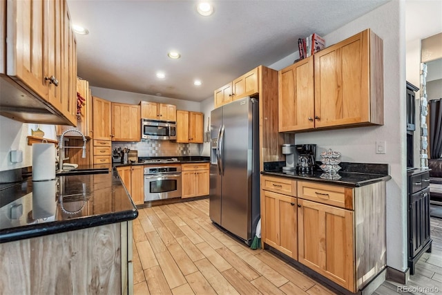 kitchen featuring stainless steel appliances, a sink, light wood-style flooring, and tasteful backsplash