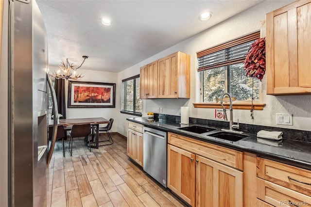 kitchen featuring light brown cabinets, stainless steel appliances, light wood finished floors, and a sink