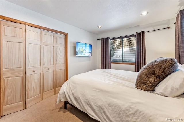 bedroom with recessed lighting, a closet, and light colored carpet