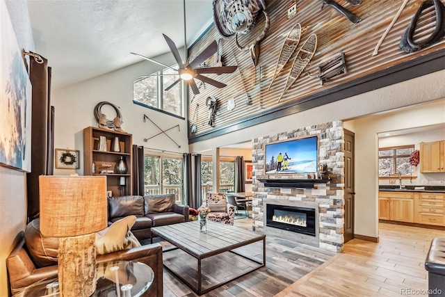 living area with light wood finished floors, ceiling fan, a fireplace, and a wealth of natural light