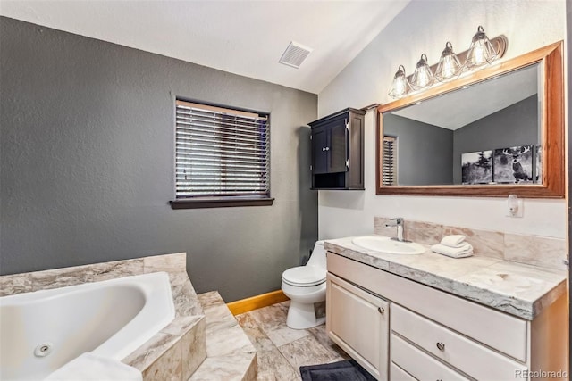 bathroom featuring visible vents, a textured wall, toilet, vanity, and a tub with jets