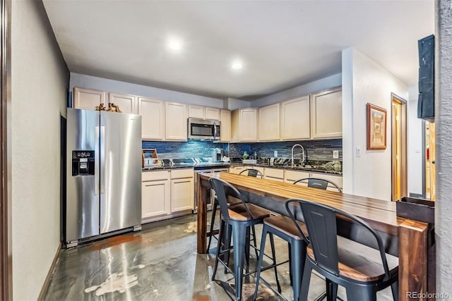 kitchen with concrete flooring, appliances with stainless steel finishes, dark countertops, and tasteful backsplash