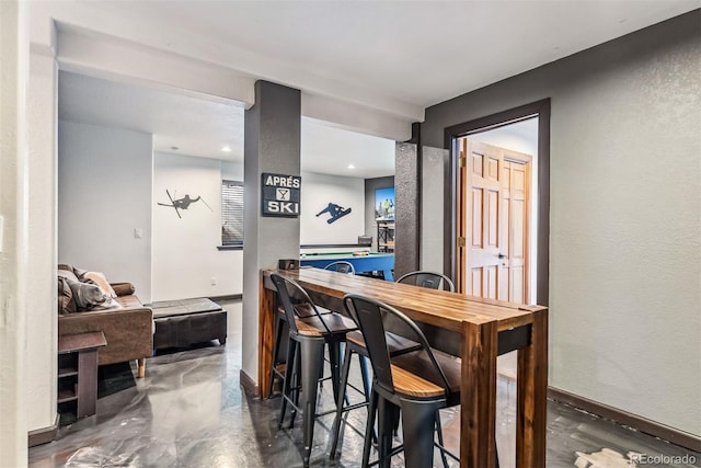 dining area with concrete floors, baseboards, and a textured wall