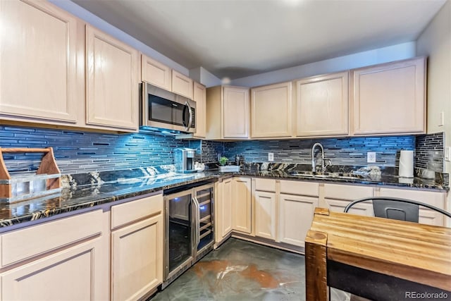 kitchen featuring beverage cooler, a sink, backsplash, dark stone counters, and stainless steel microwave