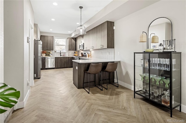 kitchen featuring dark brown cabinets, stainless steel appliances, decorative backsplash, kitchen peninsula, and light parquet flooring