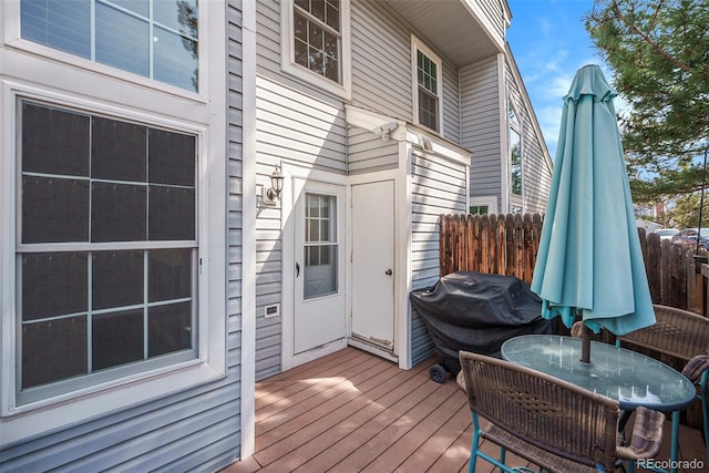 wooden terrace featuring grilling area, outdoor dining space, and fence