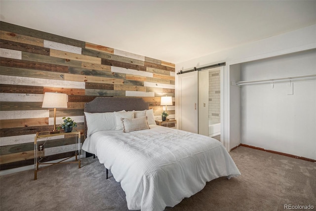 carpeted bedroom featuring wooden walls and a barn door
