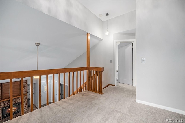 hall featuring a high ceiling, baseboards, an upstairs landing, and carpet floors