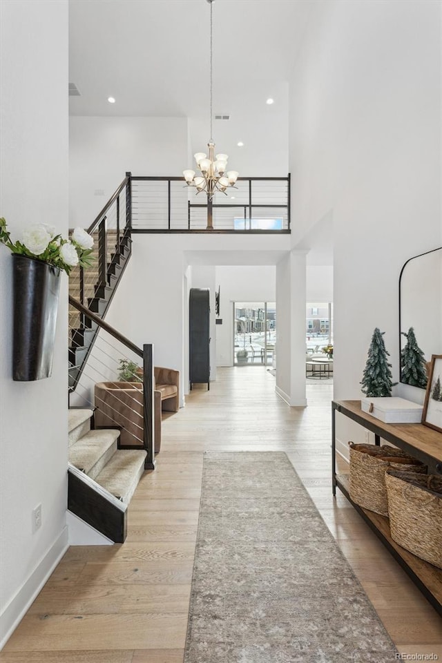 entryway featuring a towering ceiling, an inviting chandelier, and light hardwood / wood-style floors