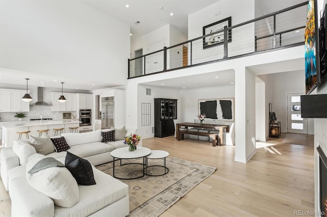 living room with sink, a high ceiling, and light wood-type flooring