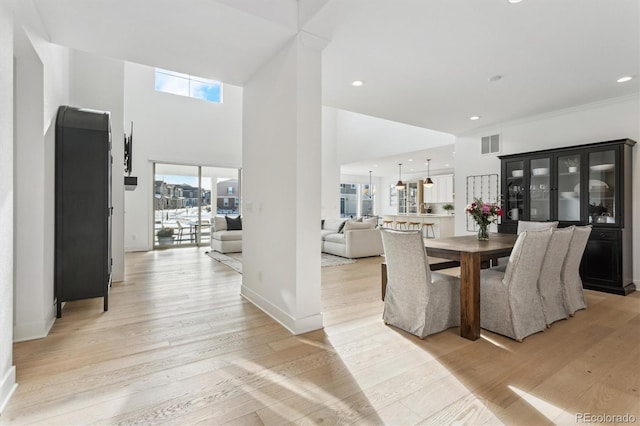 dining space with light hardwood / wood-style floors and a high ceiling