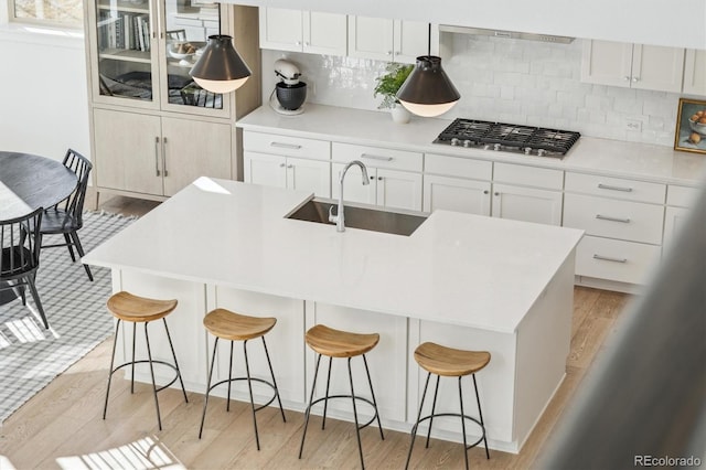 kitchen with white cabinetry, stainless steel gas stovetop, a breakfast bar, and sink