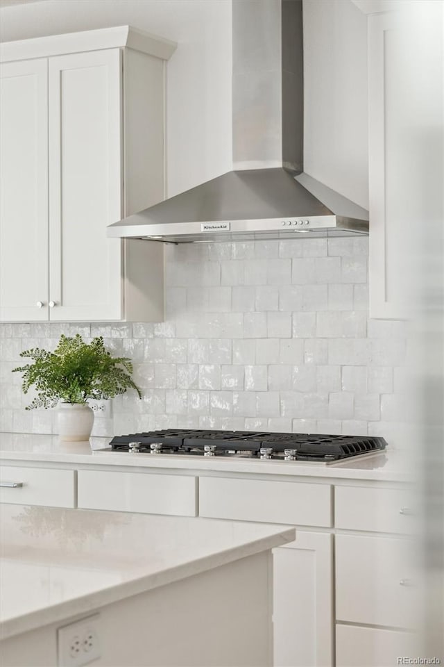 kitchen featuring white cabinetry, wall chimney range hood, backsplash, and stainless steel gas cooktop