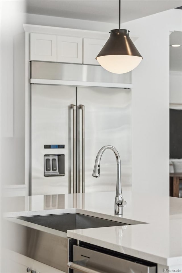 kitchen featuring appliances with stainless steel finishes, sink, hanging light fixtures, and white cabinets