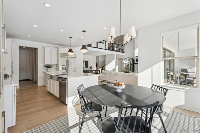 dining space with sink, a notable chandelier, and light hardwood / wood-style floors