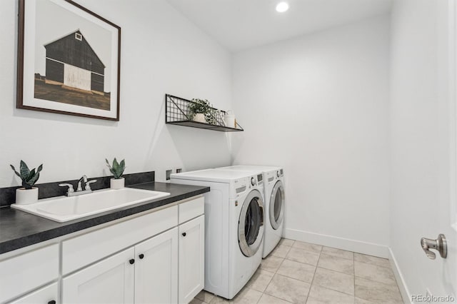 washroom featuring sink, light tile patterned floors, washer and clothes dryer, and cabinets