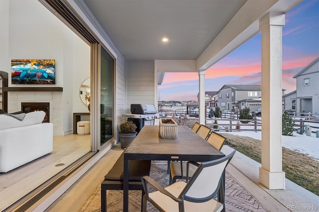 snow covered back of property featuring a grill, a fireplace, and a patio area