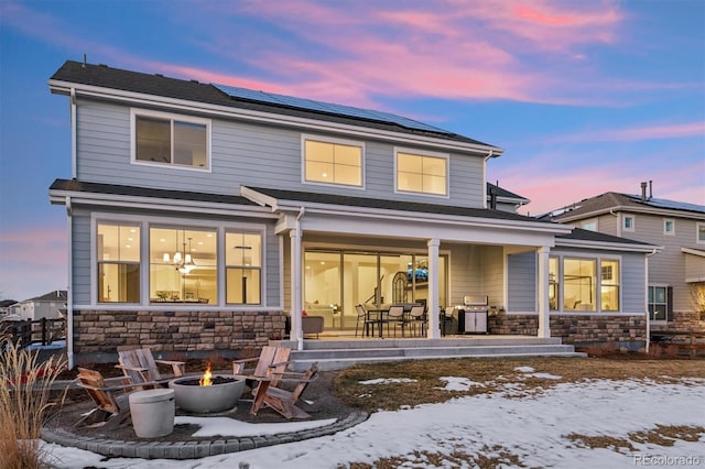 snow covered house with solar panels and an outdoor fire pit