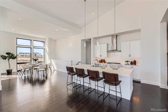 8648 Carneros Ct, Parker, CO 80138 - kitchen with wall chimney range hood, a breakfast bar area, light countertops, a center island with sink, and tasteful backsplash