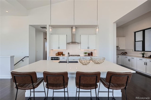 8648 Carneros Ct, Parker, CO 80138 - kitchen featuring wall chimney exhaust hood, dark wood-type flooring, decorative backsplash, a breakfast bar, and recessed lighting